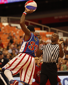 Bull points accusingly at the refere as a Globetrotter dancer looks on in the background. 