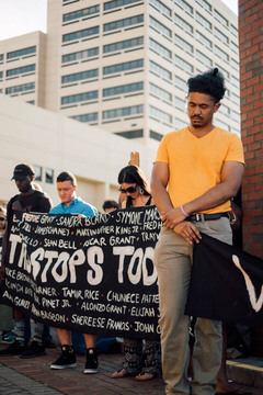 During a moment of silence, people held up a banner that listed the names of multiple victims of police violence. 