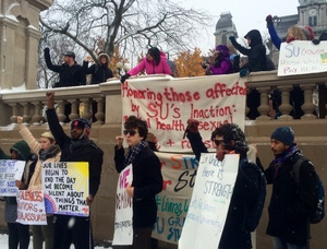 Protesters hold signs during a rally in front of the Hall of Languages on Friday afternoon.