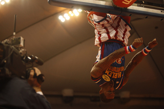 Bull hangs upside down on the rim after completing a thunderous dunk.