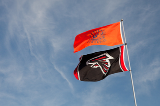 Syracuse natives and alumni raise a Syracuse and Falcons flag in a parking lot outside of the Georgia Dome.