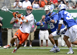 A Syracuse player slides by two Duke defenders and winds up to shoot.