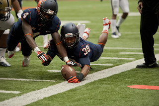 Orange linebacker Cameron Lynch and cornerback Brandon Reddish dive to recover a loose ball on the sideline.