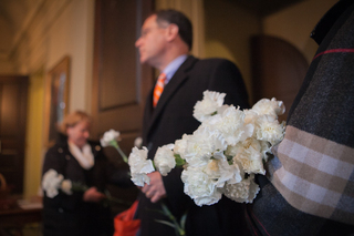 Interim Chancellor Eric Spina takes a white flower as he proceeds to the Wall of Remembrance. 