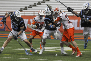 Syracuse attack Dylan Donahue pushes away a JHU player as a Blue Jay goes to scoop up the ground ball.